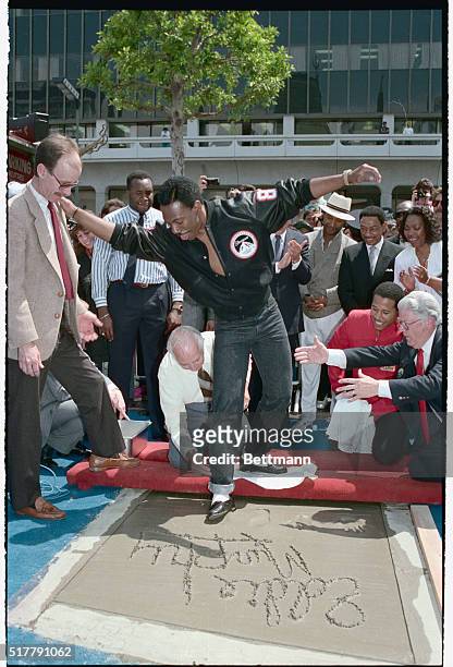Hollywood: Comedian Eddie Murphy almost leaves more than his hand and foot prints in the concrete of Mann's Chinese Theater 5/14 as he steadies...