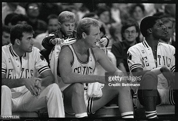 Boston Celtic Larry Bird has his sweat jacket placed on him by a ballboy during Birds first pre-season game, since sitting out the majority of the...