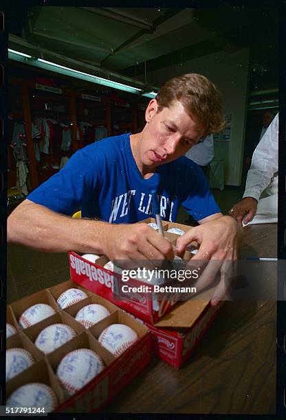 Los Angeles Dodgers pitcher Orel Hershiser does some assembly line autographing as he signs baseballs in the National League locker room before the...