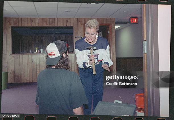 Orlando, Fla.: Tammy Faye Bakker playfully wields a hammer as a carpet layer looks on. Mrs. Bakker was at the site of her new ministry south of...