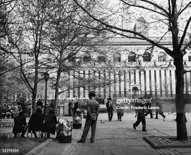 View of Bryant Park, designed by architect Thomas Hastings, as pedestrians walk past and others relax on park benches, New York, New York, 1950s. The...