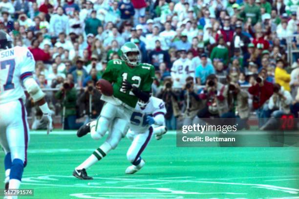 Eagles' quarterback Randall Cunningham scampers for a 14-yard gain as he avoids the tackle attempt by New York's Lawrence Taylor during first quarter...
