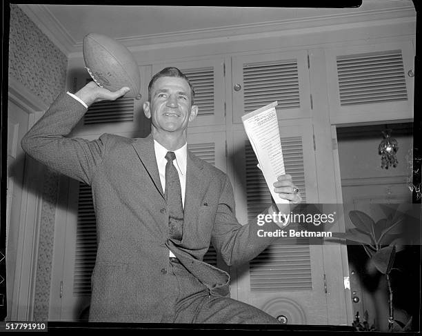 Contract in one hand and a football in the other, Slingin' Sammy Baugh, history, is in high spirits after being named head coach of the New York...