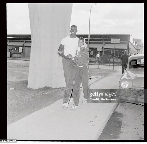 Basketball star Walt Bellamy, six feet, 11 inches tall, hugs American sprint star Wilma Rudolph during a stroll through the Olympic Village here,...