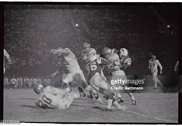 Dallas Texans halfback Johnny Robinson is brought down and tackled on a 14 yard gain by Los Angeles Chargers Dick Harris and Ron Nery in the first...