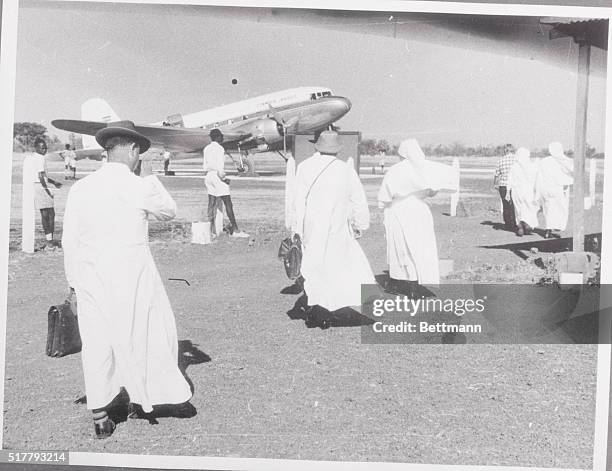 Shadow over Sudan . White-robed nuns and priests walk toward a Sudan Airways plane for the flight out of the country after being expelled January 1,...