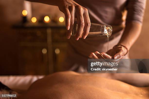 close-up of massage therapist pouring massage oil in hand. - naturopath stock pictures, royalty-free photos & images