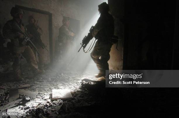 Stepping next to the burnt body of an insurgent, U.S. Marines of the Light Armored Reconnaissance company of 1st Battalion 3rd Marines, clear houses...