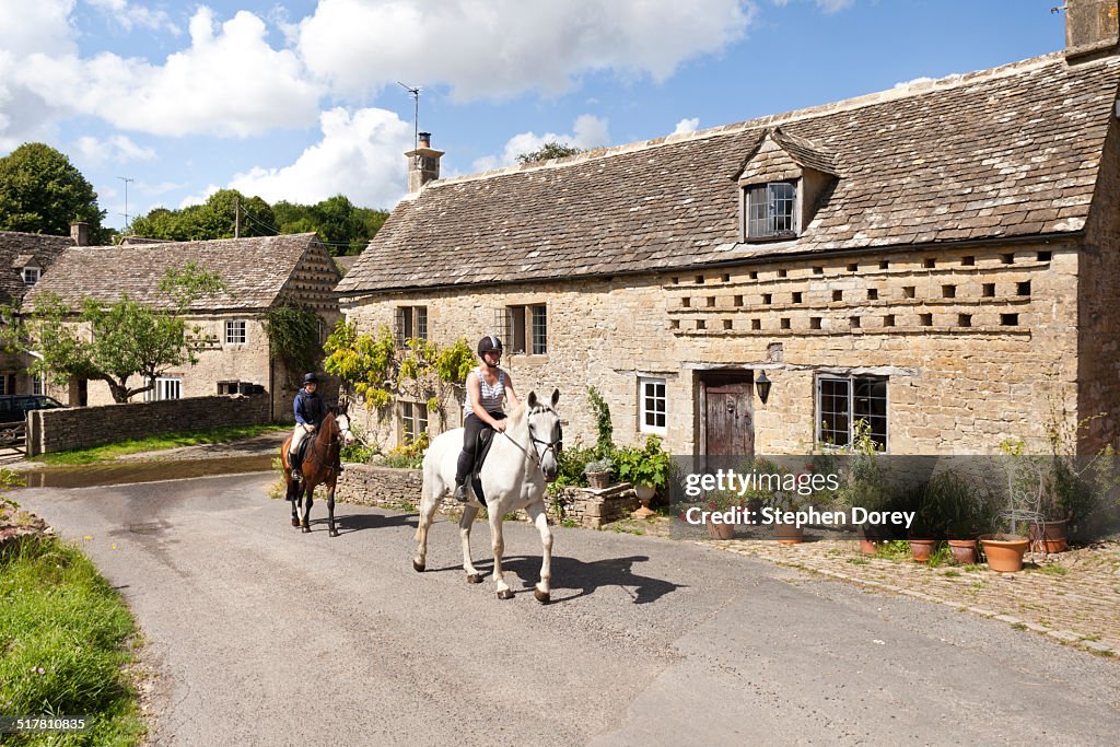 Horse riders in a Cotswold village, Glos. UK