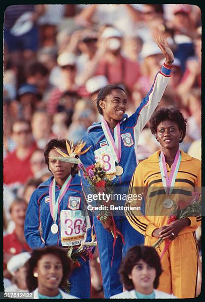 Los Angeles: U. S. Athletes Evelyn Ashford, gold winner, and Alice Brown, bronze winner, wave from the awards podium after receiving their medals for...