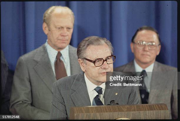 Nelson Rockefeller speaks as Gerald Ford and unknown look on.