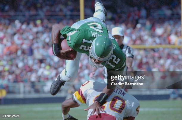 Washington: Philadelphia Eagle quarterback Randall Cunningham is upended by Redskin safety Alvin Walton during the second quarter of their game. The...