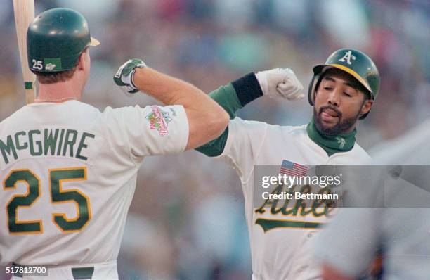 Oakland, Calif.: A's Harold Banes tags elbows with teammate Mark McGuire during the 2nd inning after hitting a home run.