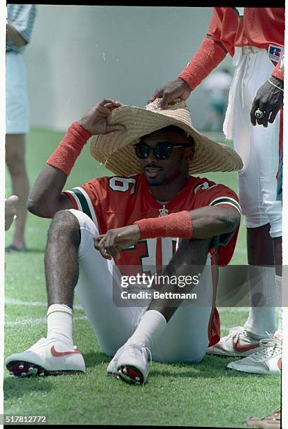 Coral Gables, Fla.: University of Miami Hurricanes' wide receiver Lamar Thomas tries to beat the heat and hang on to his hat as a teammate makes a...