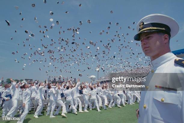Navy midshipman looks on as the U.S. Naval Academy class of 1991 toss their caps into the air at the conclusion of their graduation ceremony 5/29. A...