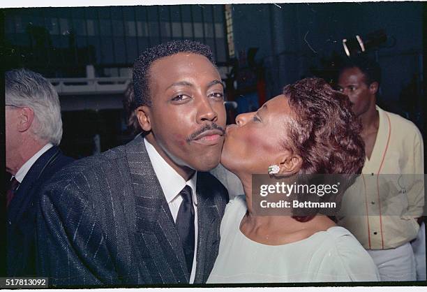 Hollywood: Arsenio Hall gets a "break a leg" kiss from his mother, Annie Hall, as he attends the premiere screening of Coming To America in which he...