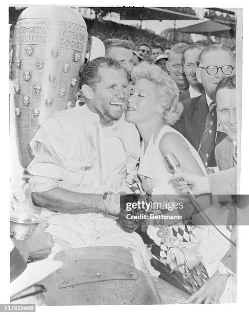 Indianapolis, Indiana: Songstress Dinah Shore plants a victory kiss on the grease covered face of Bob Sweikert, winner of the 39th Annual Auto Race...