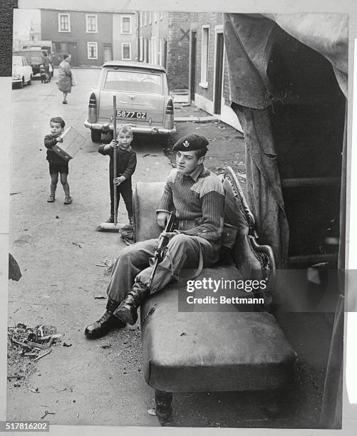 Kindness amid the Hatred: A British soldier on sentry duty recently in the Falls Road district takes it easy on a couch, supplied by local residents,...