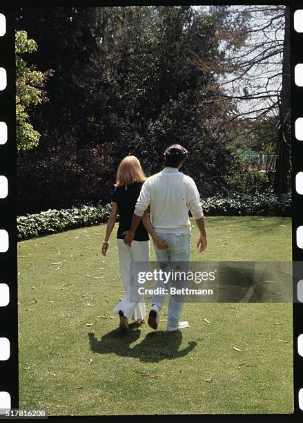 Composer Burt Bacharach plays the piano in his Hollywood home June 3rd, while his wife actress Angie Dickinson stands by.