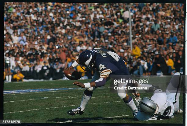 Pasadena, Calif.: Minnesota back, Chuck Foreman gains short yardage as Oakland's Willie Wall is able to catch him and bring him down during first...