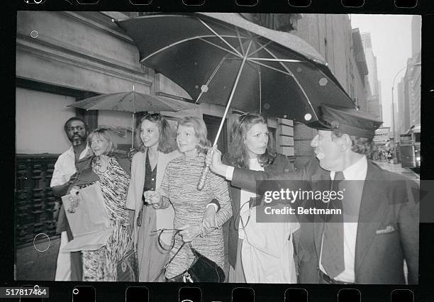 Former screen queen Rita Hayworth and her daughter, Yasmin Kahn get some protection from the rain as they leave the Mark Hellinger Theatre with Kitt...