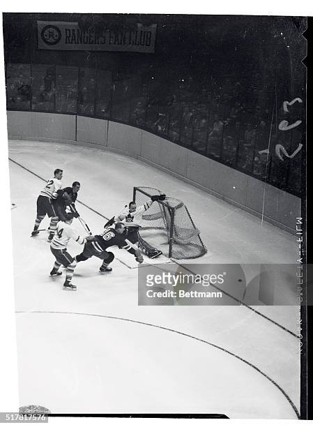 Goalie Gil Mayer of the Toronto Maple Leafs deflects the puck as Dave Creighton of the Rangers starts after it during the second period of the game...