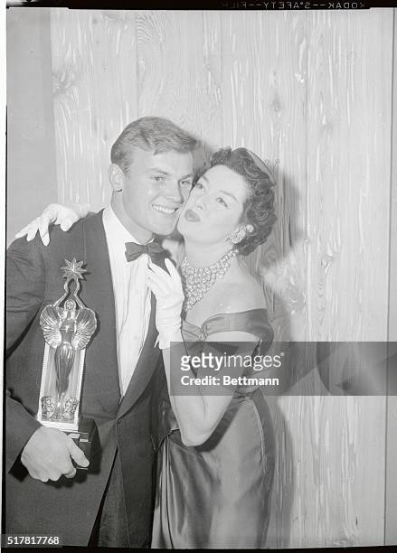 Actress Rosalind Russell bestows a congratulatory kiss on the cheek of actor Tab Hunter after presenting him with his Audie trophy as the most...