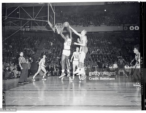 Big Ray Felix of the Knicks, jumps up and takes a rebound from the outstretched hand of John Kerr , of Syracuse), while Ken Sears , of the Knicks...