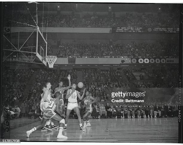 San Francisco's phenomenal Bill Russell stands with one of his huge arms poised to knock down the ball that Uclans' Willie Naulls is about to grab....