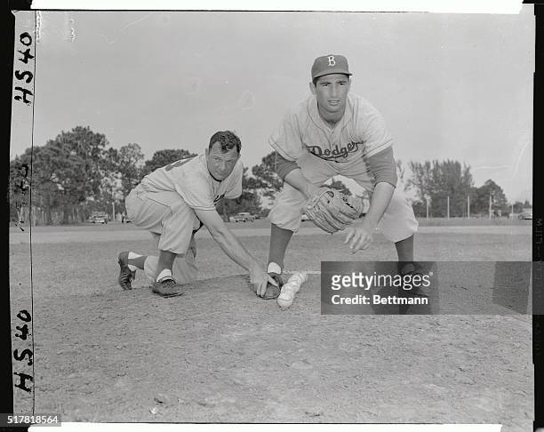 Sandy Koufax makes his delivery as coach Joe Becker checks for straightness by putting his hand on Koufax's foot to see how close he came to the line...