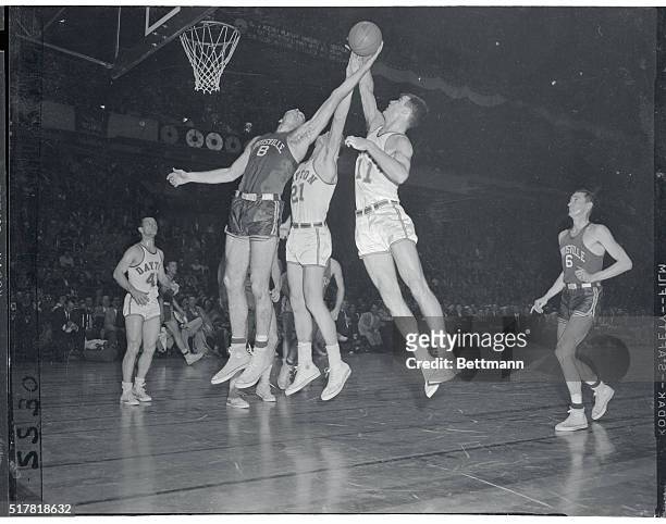 Louisville's center Charlie Tyra contends for the sphere in mid-air with Dayton's seven foot Bill Uhl and Jim Paxon in the first half of their N.I.T....