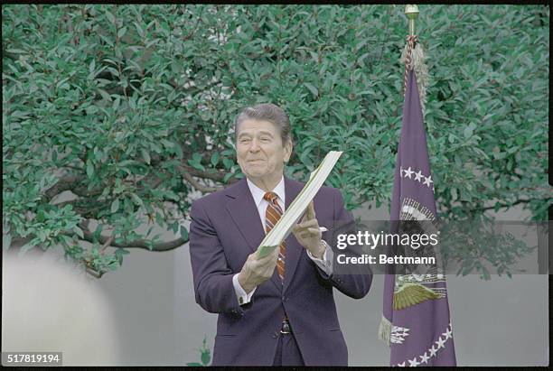 Washington, DC: President Reagan holds the Welfare Reform Bill after signing it into law October 13 in the Rose Garden of the White House.