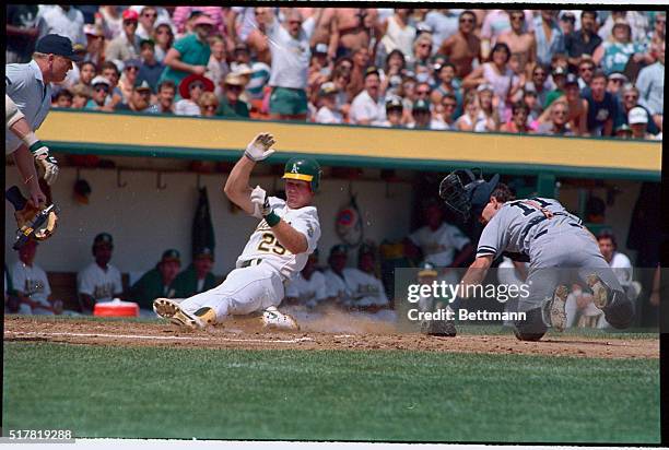 Oakland, Calif.: Mark McGwire of the Oakland Athletics slides at the plate to score past catcher Don Slaught on a Terry Steinbach double in second...