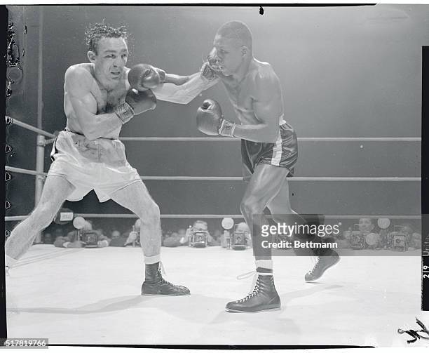 Defending welterweight champ Carmen Basilio ducks attack by challenger Johnny Saxton during the 12th round of the title bout here March 14. Saxton...