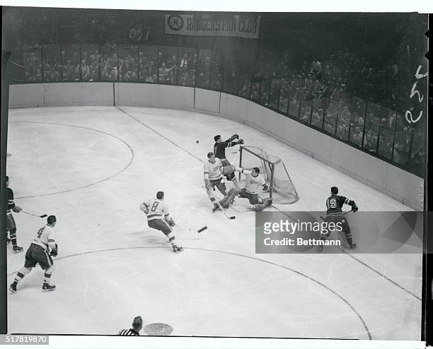 Detroit goalie Glen Hall sends the puck flying to prevent a scoring drive by Rangers' Dean Prentice in the second period of their game at the Garden...