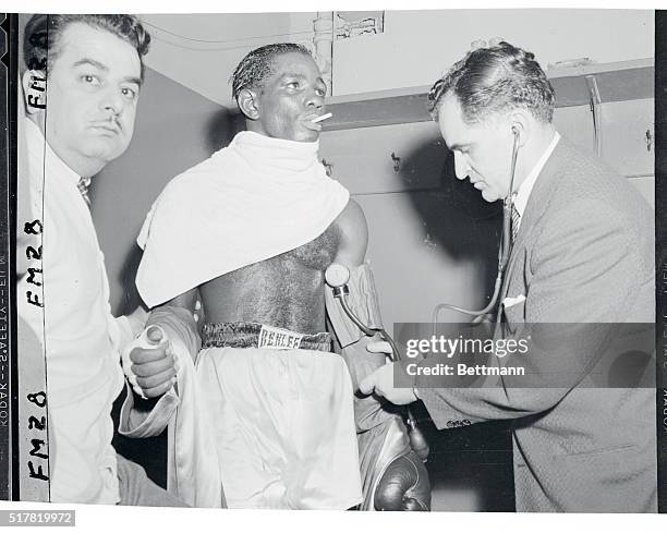 Dr. Harold Kleinman takes the blood pressure and temperature of Isaac Logart, Cuban welterweight, after the latter decisioned Virgil Akins at the...