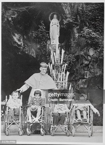 Cardinal Cushing, archibishop of Boston, and sick American children at first mass said in front of Lourdes Massabielle Grotto on the occasion of a...