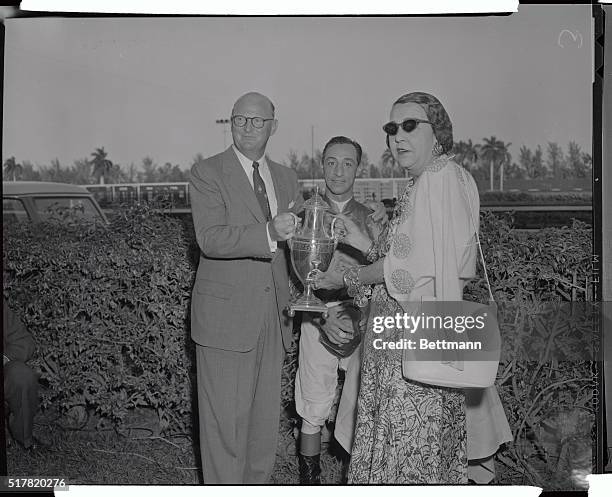 Leslie Combs, the owner of Nashua is shown here with jockey Eddie Arcaro, as Mrs. Fifi Widener Bigelow presents the Widener Trophy.