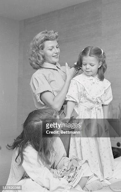 Mother's touch...Herself apparently full of joy because her daughters get along so well with her new husband, Rita beams as she combs Yasmin's hair....