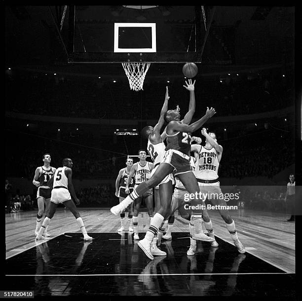 Elgin Baylor of the Lakers balances the ball on his fingertips as he takes off a rebound during the game against Detroit here Nov. 21. Also battling...