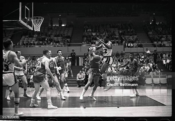 Dave Gambee of the Syracuse Nets, slaps the ball out of Elgin Baylor's hand as the Laker high scorer tries for a first period score. The referee...