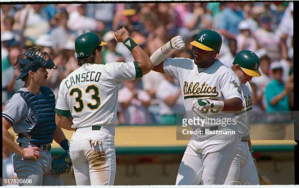 Oakland, Calif.: Oakland's Dave Parker gets an arm bash from Jose Conseco after hitting a two run homer in the third inning against the New York...