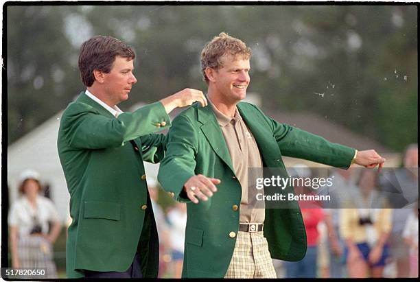 Augusta, GA- Scotland's Sandy Lyle slides into the traditional green jacket with the help of last year's Masters winner, Larry Mize, after Lyle won...