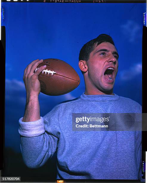Notre Dame quarterback Johnny Lujack is shown yelling and holding a football in this head and shoulders photograph.
