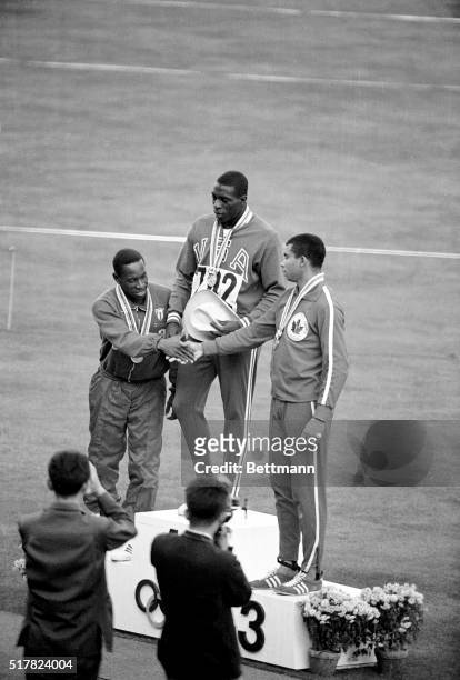 America's Bob Hayes, winner of the gold medal in the Olympic 100-meter dash, is flanked by silver medalist E. Figerola of Cuba and bronze medal...
