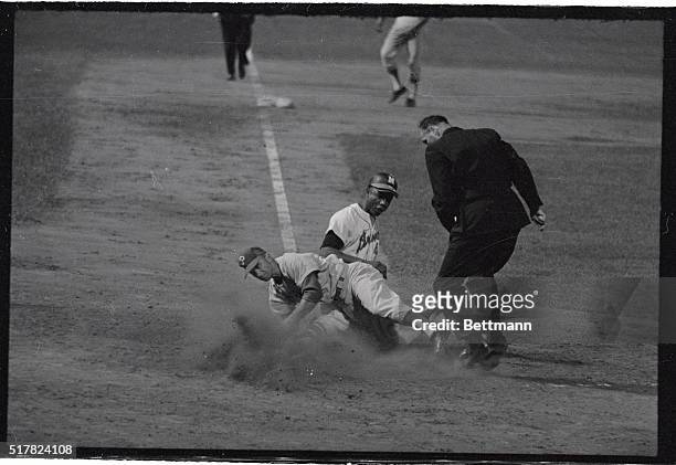 Bobby Shantz, Philadelphia Phillies pitcher is knocked off his feet covering the home plate here, as Milwaukee Braves right fielder Hank Aaron scores...