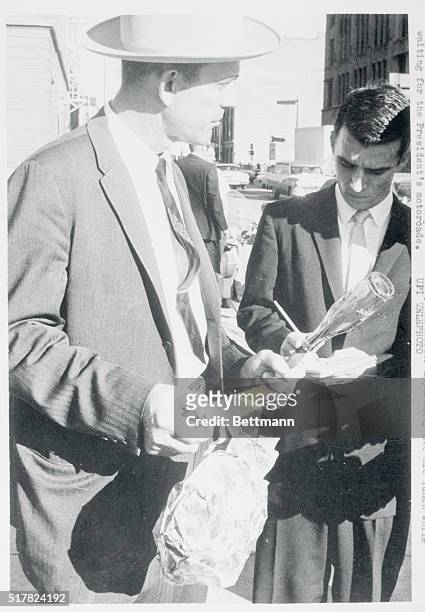 Dallas: A member of the Dallas Crime Lab holds a lunch sack and drink bottle which was found at sniper Lee Harvey Oswald's hideout. The killer...