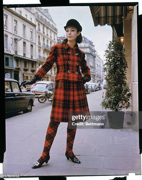 Christina, youngest model in Paris, showing a red and black plaid skirt suit with matching plaid stockings for the Castillo Fall collection. She is...