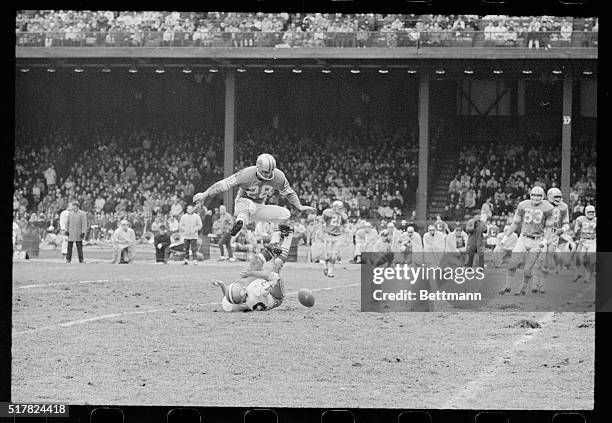 Lions' defensive back Yale Lary jumps high to avoid landing on 49er's halfback Dave Kopay who had just missed a pass from quarterback John Brodie...