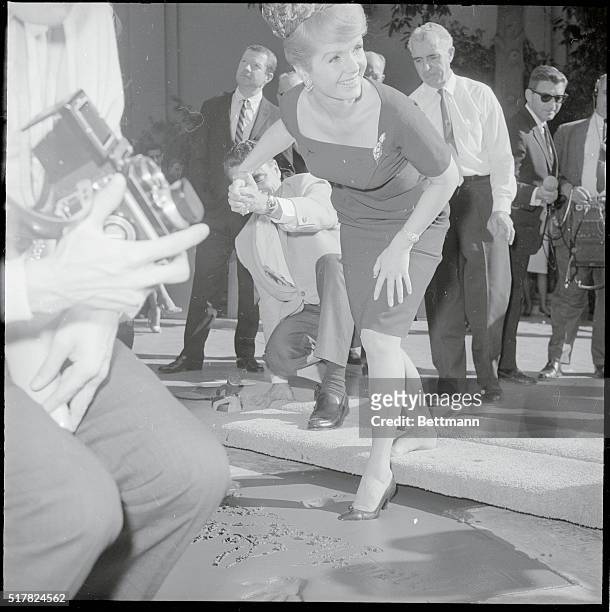 Actress Debbie Reynolds puts her foot imprint in the wet cement in the forecourt of Grauman's Chinese Theater. She also put her hand prints and...